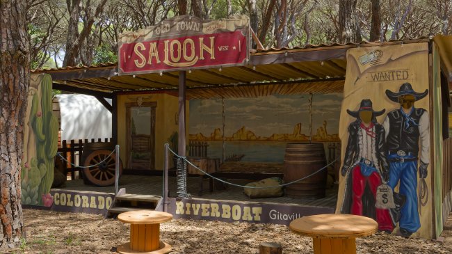 Scenografia di un saloon western tra gli alberi.