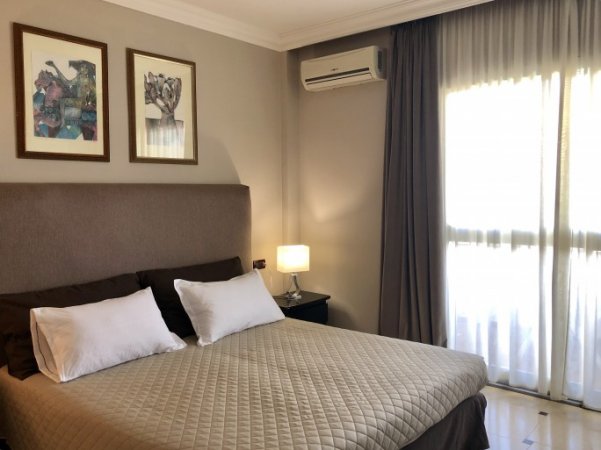 Camera da letto con letto matrimoniale, lampada da tavolo, e due quadri sopra il letto.