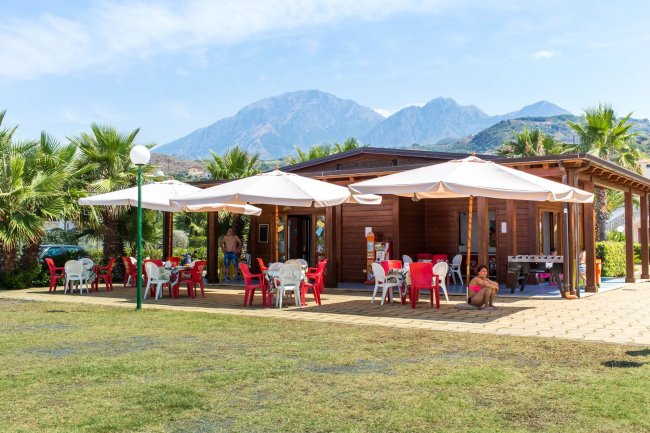 Struttura in legno con sedie all'aperto e ombrelloni.