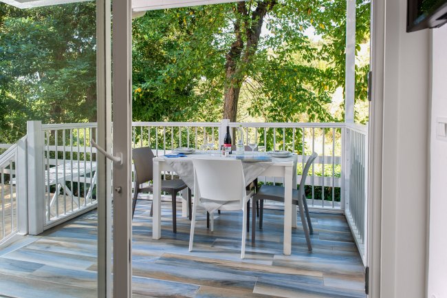 Tavolo apparecchiato su una veranda con vista su alberi verdi.