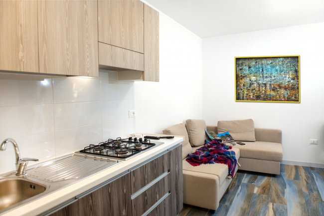 Cucina moderna con lavello, fornelli, un divano beige e un dipinto colorato su parete.