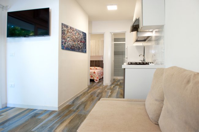 Interno con cucina, soggiorno e TV a parete.
