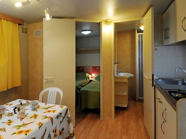 Interno di un bungalow con tavolo, sedie e cucina.