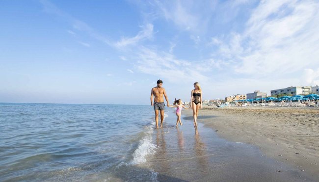 Una famiglia cammina sulla spiaggia vicino al mare.