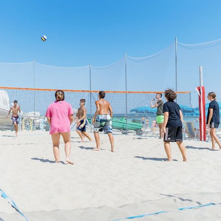 Gruppo di persone gioca a pallavolo sulla sabbia.
