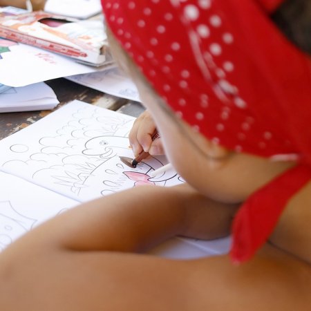 Bambino con bandana rossa che colora un libro da colorare.