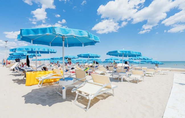 Lettini e ombrelloni blu sulla spiaggia soleggiata.