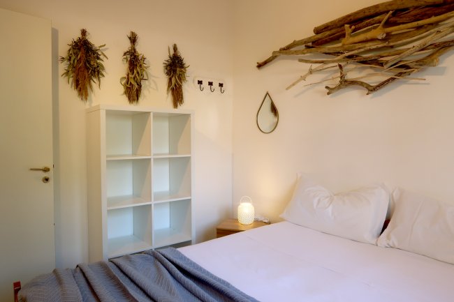 Camera con letto bianco e decorazioni naturali.