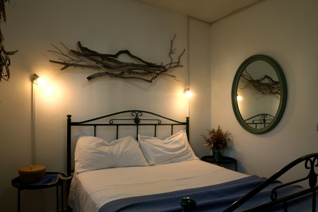 Camera con letto in ferro e specchio tondo.
