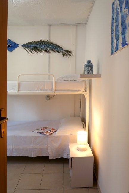 Camera con letto a castello, lampada sul comodino e decorazioni murali blu.