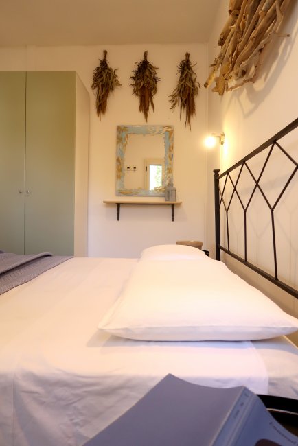 Camera da letto con letto matrimoniale, specchio, decorazioni murali e armadio verde.