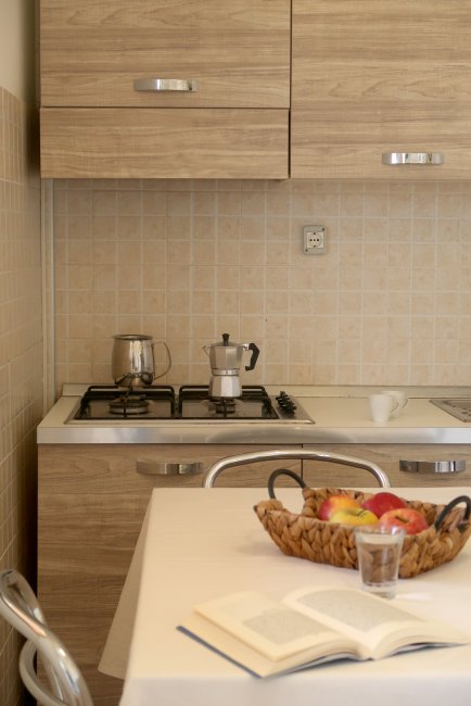 Cucina con fornello, cesta di frutta e libro aperto.