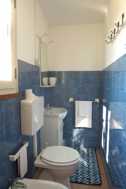 Bagno con piastrelle blu, lavandino e wc.