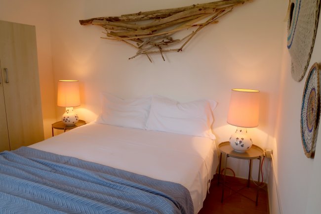 Camera con letto matrimoniale e decorazioni in legno sul muro.