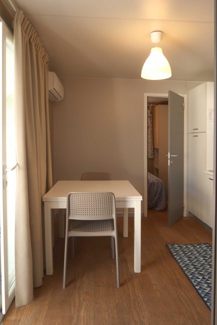 Sala da pranzo con tavolo bianco e sedie, luce soffusa.