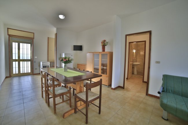 Sala da pranzo con tavolo, sedie e vetrina.