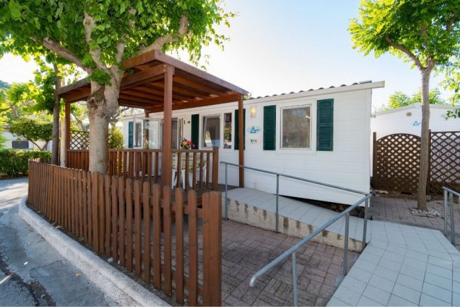 Casa mobile bianca con veranda e staccionata.