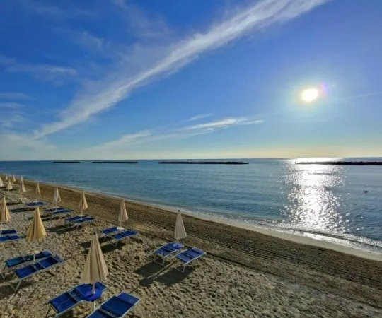 Spiaggia sabbiosa al tramonto con ombrelloni.