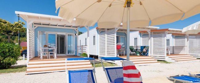 Bungalow su una spiaggia con lettini e ombrelloni.