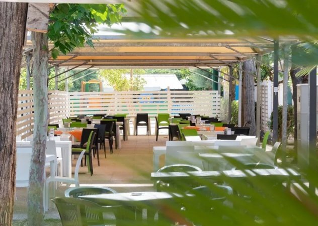 Area ristorazione all'aperto con tavoli e sedie colorate.