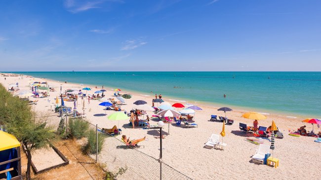 Spiaggia affollata con ombrelloni colorati.