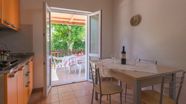 Cucina con tavolo apparecchiato vista su terrazza.