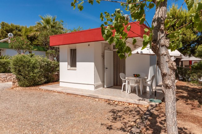 Piccola casa bianca con tavolo e sedie all'esterno.