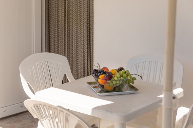 Tavolo bianco con vaschetta di frutta e sedie.