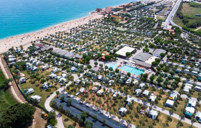 Vista aerea di un campeggio con spiaggia sabbiosa.