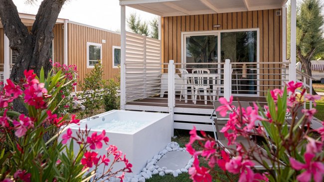 Veranda di bungalow con vasca e fiori rosa.