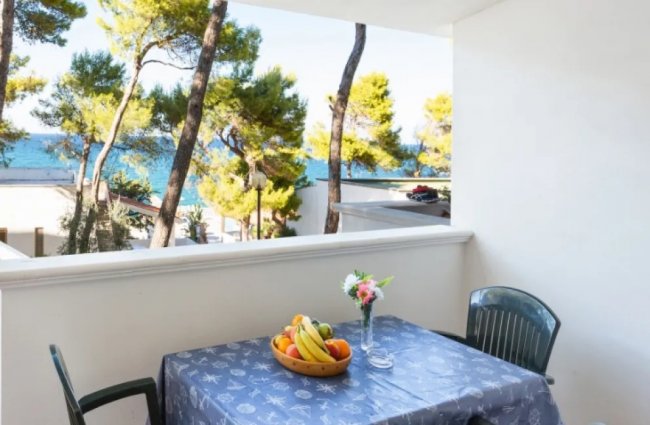 Tavolo su terrazza con vista su alberi e mare.
