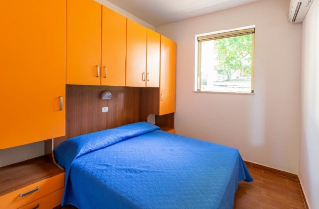 Camera con letto matrimoniale e armadio arancione.