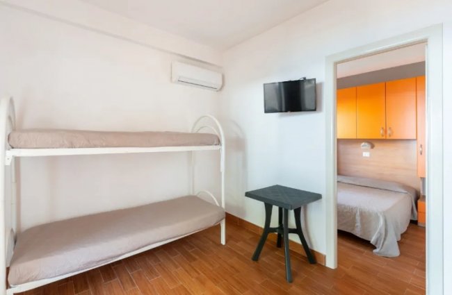 Letti a castello e una TV in una stanza ben illuminata.