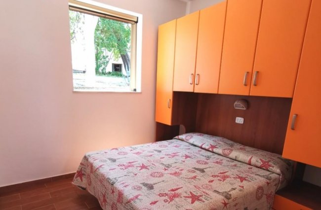 Camera da letto con armadi arancioni sopra il letto.