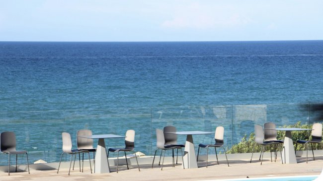 Tavolini e sedie con vista sul mare azzurro.