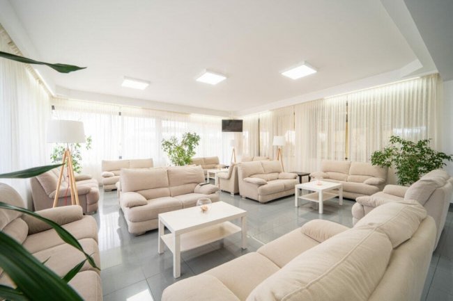 Lounge con divani beige e piante.