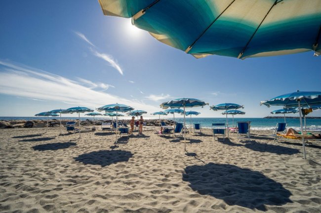 Spiaggia con ombrelloni blu sotto il sole.