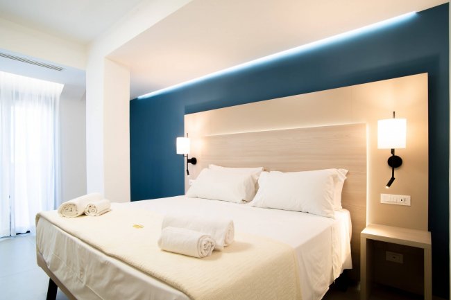 Camera moderna con letto matrimoniale e luci soffuse.
