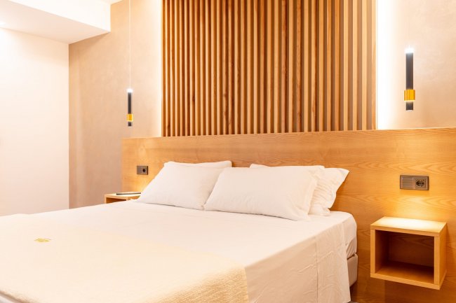 Camera elegante con letto e parete in legno verticale.