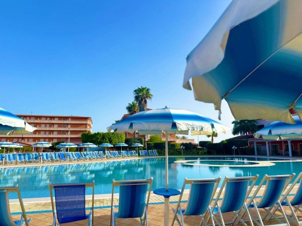 Piscina all'aperto con sedie e ombrelloni.