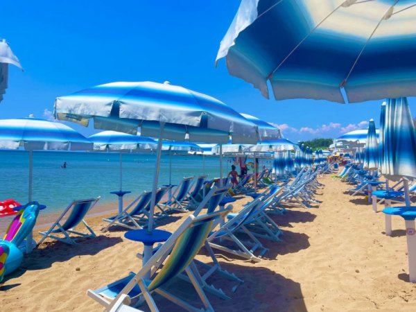 Una spiaggia con lettini e ombrelloni blu.