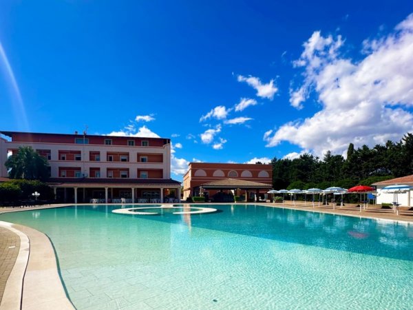 Una grande piscina vicino a un edificio rosa.