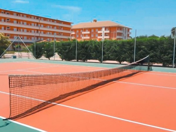 Campo da tennis arancione con edifici sullo sfondo.