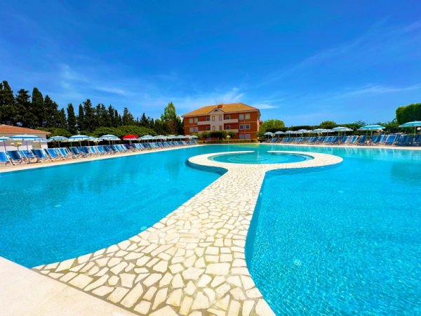 Piscina a sfioro con passerella centrale.
