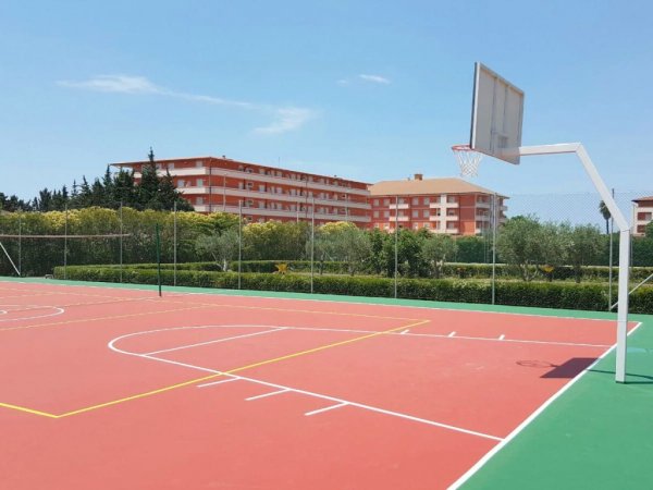 Campo da basket con palazzina sullo sfondo.