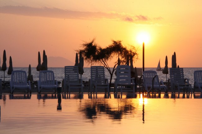 Tramonto su sedie a sdraio e ombrelloni sulla spiaggia.