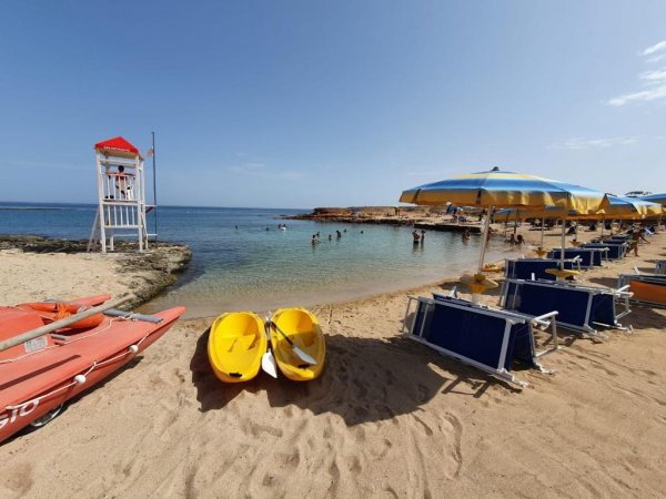 Spiaggia con sdraio, ombrelloni e canoe.