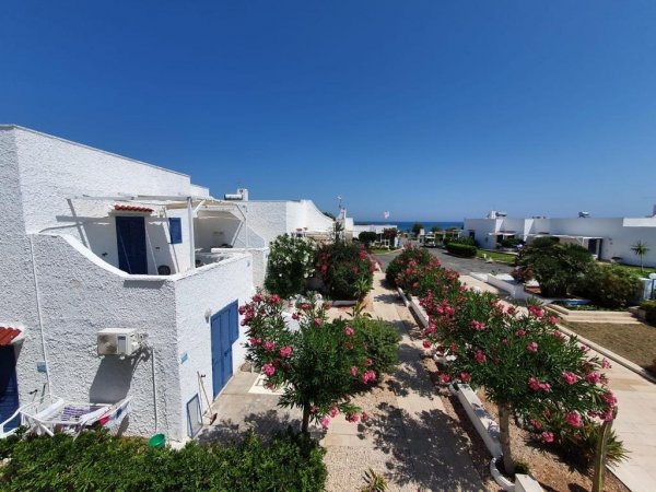 Complesso di case bianche con giardini fioriti.