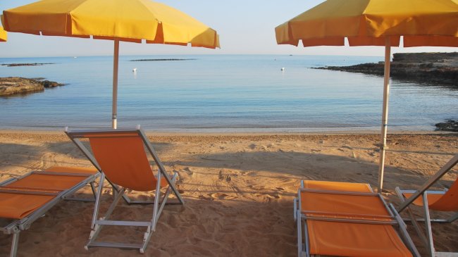 Spiaggia con lettini e ombrelloni gialli.
