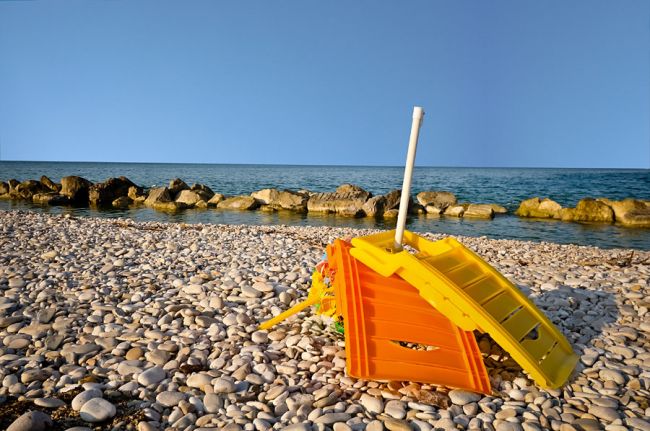 Lettino giallo e arancione su spiaggia di ciottoli.